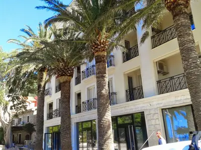 a building with palm trees in front of it at Apartments Dangubic in Petrovac na Moru