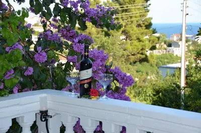 a bottle of wine sitting on a ledge with purple flowers at Apartment Dragovic in Ulcinj