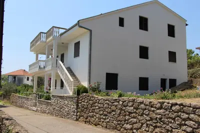 a large white house with a stone wall at Apartment Dragovic in Ulcinj