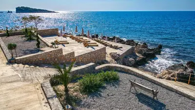 a beach with a bunch of benches and the ocean at Sunset Bay Apartments in Utjeha