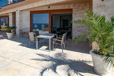 a patio with a table and chairs on a building at Sunset Bay Apartments in Utjeha