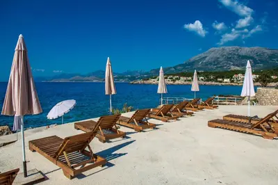 a row of chairs and umbrellas on a beach at Sunset Bay Apartments in Utjeha