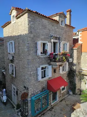 an old stone house with a red awning at Guesthouse Bogdanovic in Budva