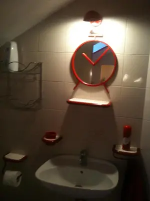a clock on a wall above a sink in a bathroom at Guesthouse Bogdanovic in Budva