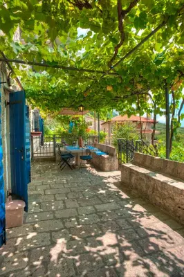 a patio with a table and chairs under a tree at Holiday Home Neda in Sveti Stefan