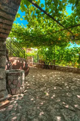 a patio with a table and chairs under a tree at Holiday Home Neda in Sveti Stefan