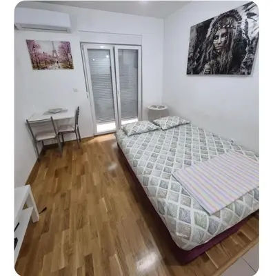 a bedroom with a bed and a table and a desk at Studio 23 in Podgorica