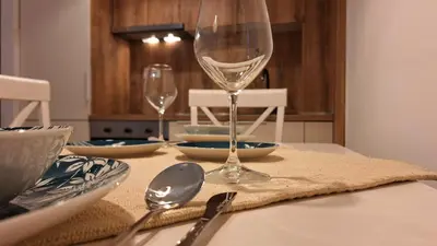a table with a wine glass and plates and silverware at Podgorica apartment in Podgorica