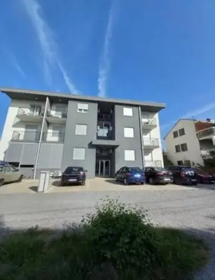 a large building with cars parked in a parking lot at Podgorica apartment in Podgorica