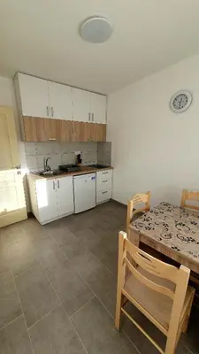 a kitchen with white cabinets and a table and a table and chairs at Deutsche Willa in Sutomore