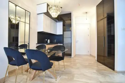 a dining room with a glass table and blue chairs at Prometheus Apartments in Budva