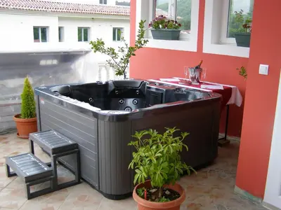 a hot tub on a balcony with a table and plants at Hotel Wellness & Spa Angelo Gabriel in Buljarica