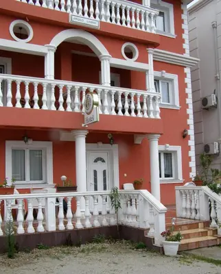 a red building with a white balcony and stairs at Hotel Wellness & Spa Angelo Gabriel in Buljarica