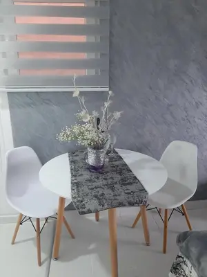 a table with two white chairs and a vase of flowers at Cozzy apartment near the Aiport Podgorica in Podgorica