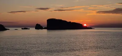 a sunset over a body of water with a rock formation at Sweet Sea Villa in Utjeha