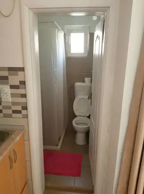 a small bathroom with a toilet and a window at Apartments Miki in Bar
