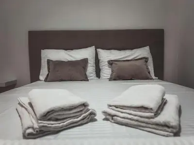 a bed with white blankets and pillows on it at Apartment Podgorica Center in Podgorica