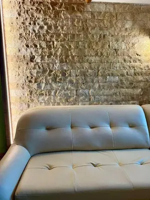 a leather couch in front of a brick wall at Shasi Eco Lodge in Ambula