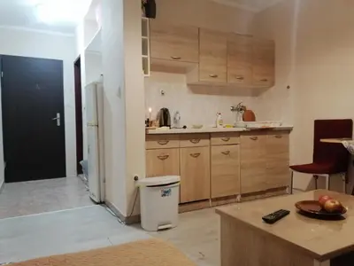 a kitchen with a refrigerator and a table with a bowl of fruit at Квартира 200м от моря. in Bar
