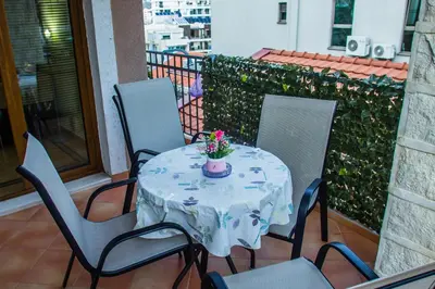 a table with chairs and a vase with flowers on it at Villa Danile Cosy Apartments in Budva