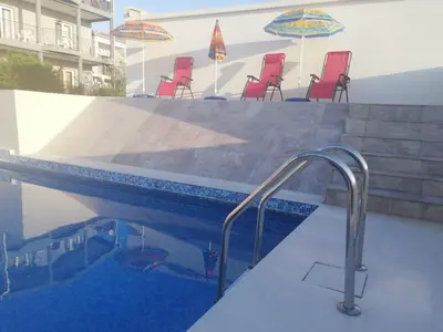 a swimming pool with red chairs and umbrellas at Apartments Svetlana in Utjeha
