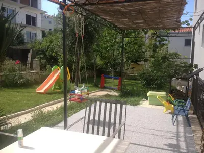 a backyard with a playground with a swing at Apartments Svetlana in Utjeha