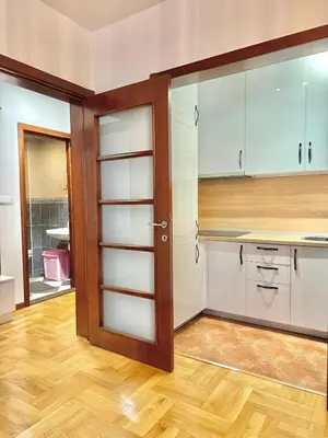 a kitchen with white cabinets and a wooden floor at Comfort Family Apartment Eva in Budva