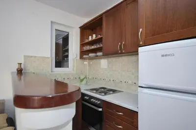 a kitchen with wooden cabinets and a white refrigerator at Apartments Spas in Budva