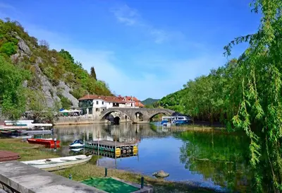 a river with a bridge and boats in the water at Apartment Jovicevic in Rijeka Crnojevića