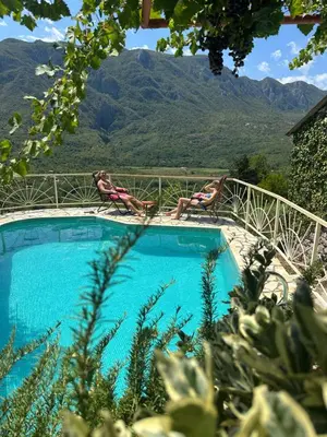 two people laying in lounge chairs by a swimming pool at Ethno House Ivanovic in Virpazar