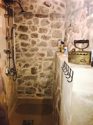 a stone bathroom with a shower and a stone wall at Ethno House Ivanovic in Virpazar