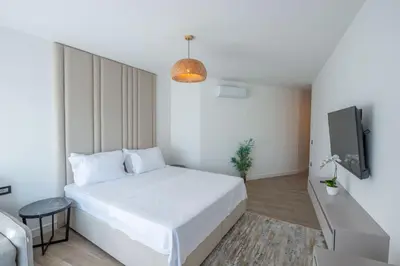 a white bedroom with a bed and a tv at Botanica Boutique Hotel in Ulcinj