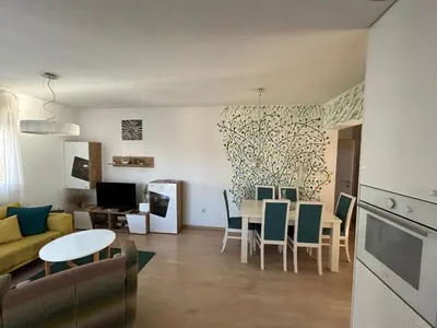 a kitchen and living room with a table and chairs at Ana’s 2 bedrooms lovely flat in Podgorica