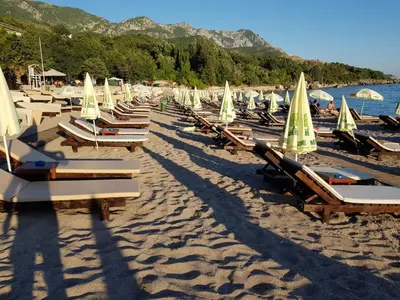 a bunch of lounge chairs with umbrellas on a beach at Lux apartment Amarin in Pržno