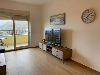 a living room with a tv and a clock on the wall at Lux apartment Amarin in Pržno