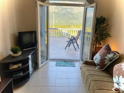 a living room with a couch and a sliding glass door at Captivating and Spacious 2-Bed House in Vranovici in Drakulovići