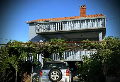 a car parked in front of a house with a balcony at Captivating and Spacious 2-Bed House in Vranovici in Drakulovići