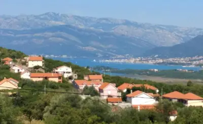 a village on a hill with mountains in the background at Captivating and Spacious 2-Bed House in Vranovici in Drakulovići