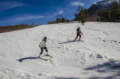 two people are skiing down a snow covered slope at Hotel Monte Rosa in Cetinje