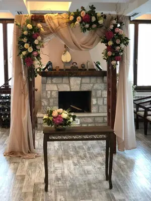 a living room with a fireplace and a table with flowers at Hotel Monte Rosa in Cetinje