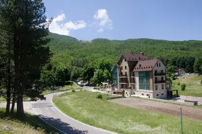 a large house on a hill next to a road at Hotel Monte Rosa in Cetinje