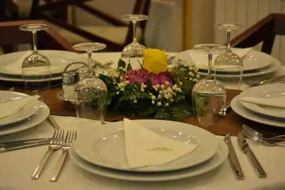 a table with white plates and flowers on it at Hotel Monte Rosa in Cetinje