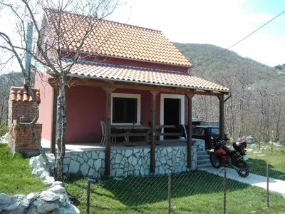 a small red house with a motorcycle parked in front of it at Holiday Home Nikolić in Njeguši