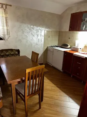 a kitchen with a wooden table and a table and chairs at Holiday Home Nikolić in Njeguši
