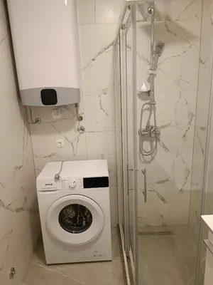 a white washing machine in a bathroom with a shower at Digital Nomads Apartments in Bar