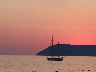 a boat sitting in the water at sunset at Digital Nomads Apartments in Bar