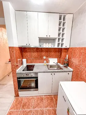 a kitchen with white cabinets and a sink at AvR Street Budva in Budva