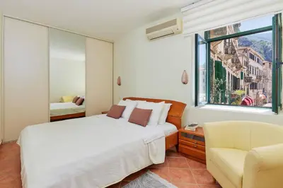a bedroom with a bed and a chair and a window at Spacious 1Bedroom on the Main Square of Kotor in Kotor