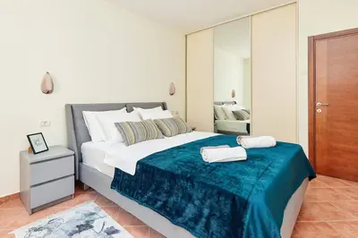 a bedroom with a large bed with a blue blanket at 1-Bedroom Flat on the Main Square in the Old Town in Kotor