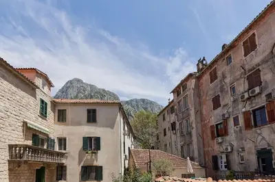 an alley with buildings and mountains in the background at 1-Bedroom Flat on the Main Square in the Old Town in Kotor